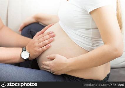 Closeup photo of man holding hands on pregnant wife belly