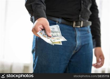 Closeup photo of man in jeans and shirt holding hundred dollar banknotes