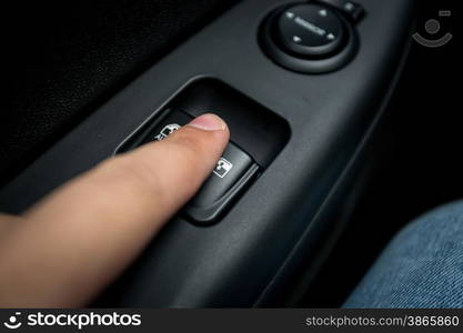 Closeup photo of man pressing button controlling window in car