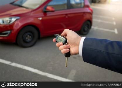 Closeup photo of man pressing the button on remote car alarm system