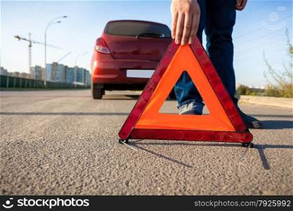 Closeup photo of man putting triangle warning sign on road