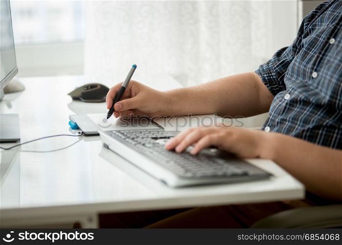 Closeup photo of man using digital graphic tablet and keyboard