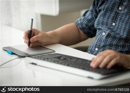 Closeup photo of man using digital graphic tablet and keyboard at office