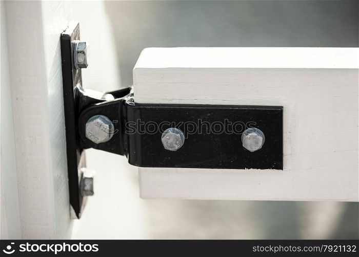 Closeup photo of metal clamp fixing two white wooden boards on bridge