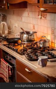 Closeup photo of metal pan boiling on burning gas stove on country style kitchen