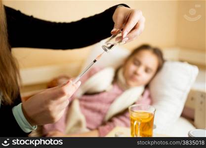 Closeup photo of mother filling syringe from ampule next to daughters bed