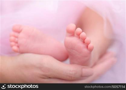 Closeup photo of mothers hand holding little baby feet, doing massage for child, happy parenthood, health care and protection concept