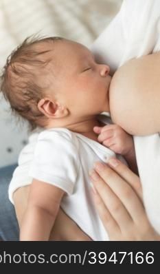 Closeup photo of newborn baby boy eating mothers breast milk