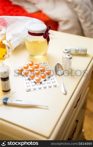 Closeup photo of pills and medicines lying on table next to bed