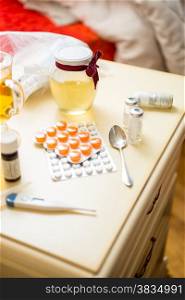 Closeup photo of pills and medicines lying on table next to bed