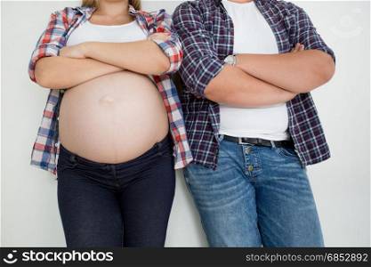 Closeup photo of pregnant woman and husband leaning on white wall