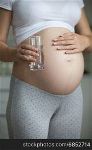 Closeup photo of pregnant woman holding glass of water