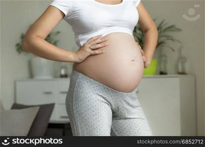 Closeup photo of pregnant woman holding hands on big belly