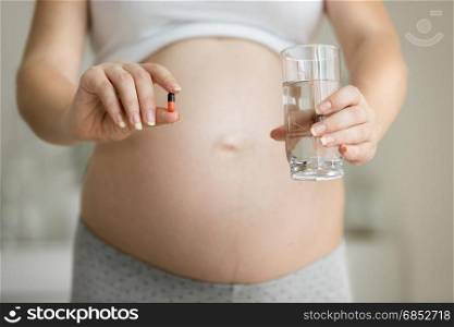 Closeup photo of pregnant woman posing with medicines