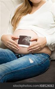 Closeup photo of pregnant woman posing with ultrasound abode image