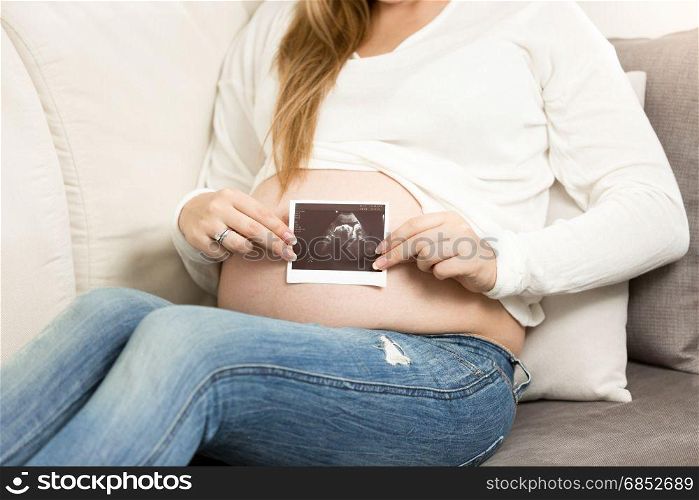 Closeup photo of pregnant woman posing with ultrasound scan