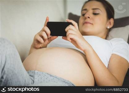 Closeup photo of pregnant woman typing message on smartphone