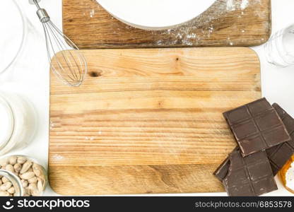 Closeup photo of rolling pin, chocolate, flour and dough lying on wooden board at kitchen