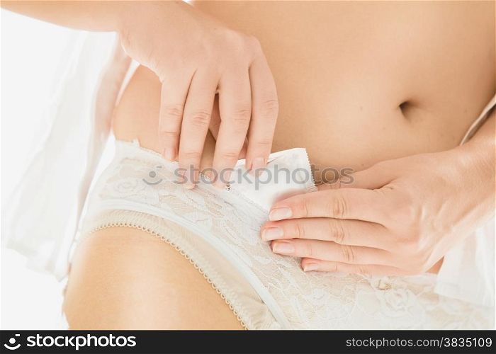 Closeup photo of sexy woman putting condom in white lace panties