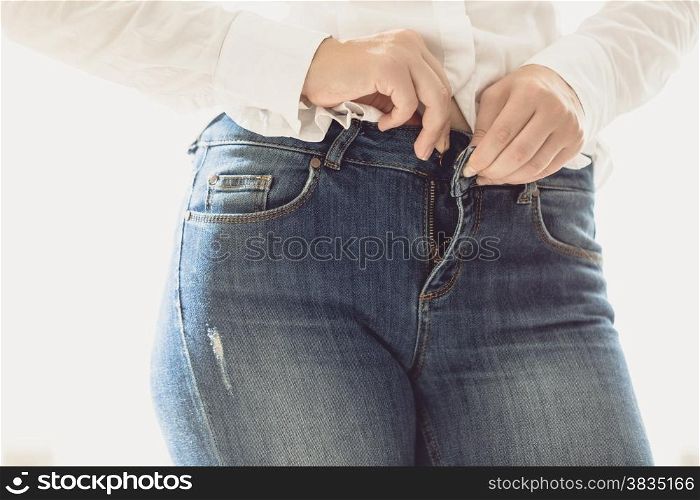 Closeup photo of sexy woman unbuttoning her jeans