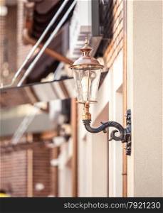 Closeup photo of street lamp on building stylized to retro gas lamp