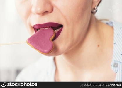 Closeup photo of the woman lips and gingerbread hearts on a stick, concept of love or valentines das