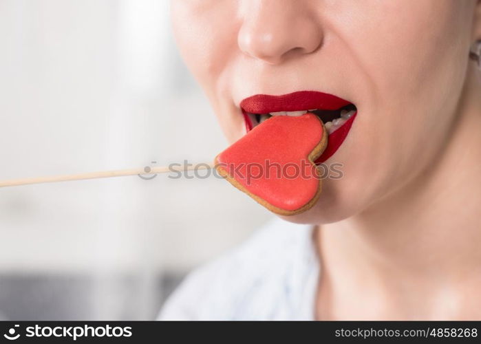 Closeup photo of the woman lips and gingerbread hearts on a stick, concept of love or valentines das