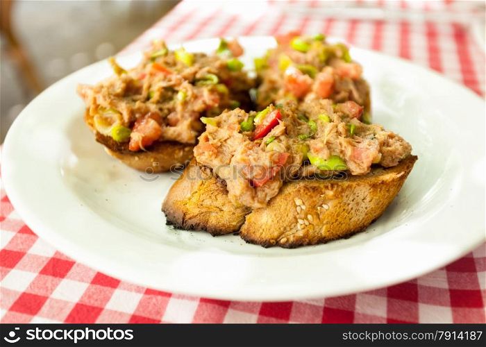 Closeup photo of three bruschettas with tuna lying on plate at restaurant