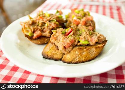 Closeup photo of three bruschettas with tuna lying on plate at restaurant