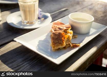 Closeup photo of traditional apple strudel with vanilla sauce on old wooden table