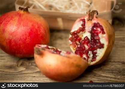 Closeup photo of two halves of pomegranate on old wooden board