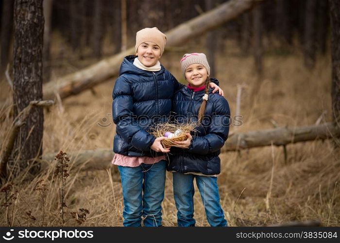 Closeup photo of two happy girls holding basket full of Easter eggs