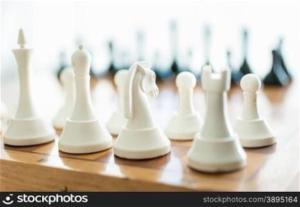 Closeup photo of white chess piece set on wooden board
