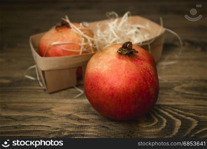 Closeup photo of whole pomegranate lying on old wooden desk