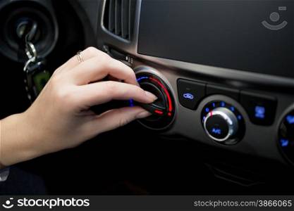 Closeup photo of woman adjusting car conditioner temperature
