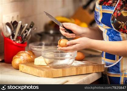 Closeup photo of woman cracking egg with knife