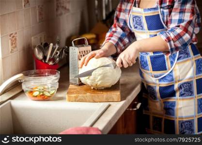 Closeup photo of woman cutting cabbage on kitchen