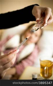 Closeup photo of woman filling syringe from ampule at sick girl&rsquo;s bed