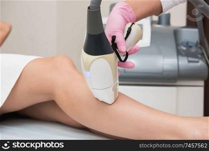 Closeup photo of woman getting laser hair removal procedure on her legs in modern clinic. Cosmetology and SPA concept. Hair removal procedure