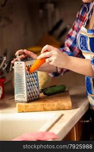 Closeup photo of woman grating carrot on wooden board