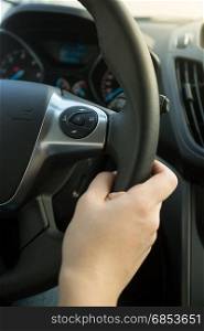 Closeup photo of woman holding leather steering wheel