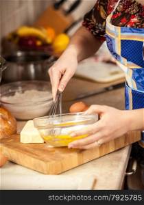Closeup photo of woman mixing eggs in glass bowl