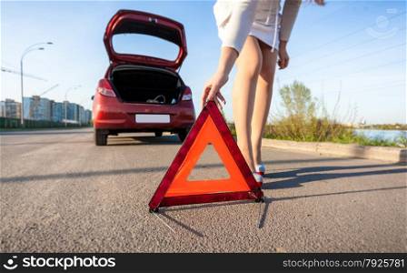 Closeup photo of woman putting warning sign after car crash