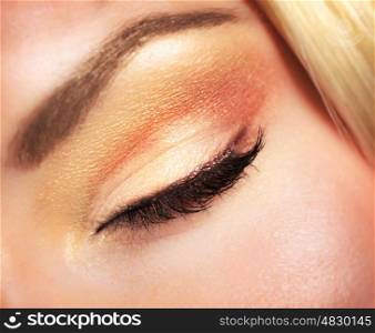 Closeup photo of woman's closed eye with beautiful golden autumnal makeup, face part of attractive model, beauty and style concept