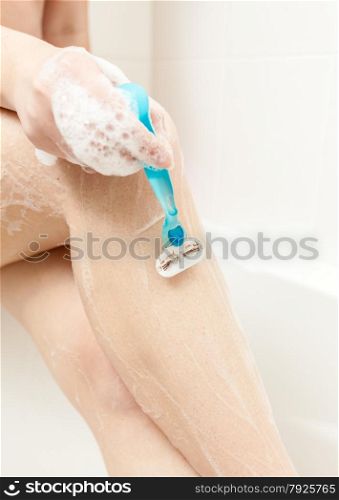 Closeup photo of woman shaving leg at bath