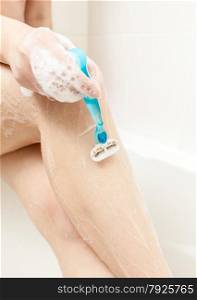 Closeup photo of woman shaving leg at bath