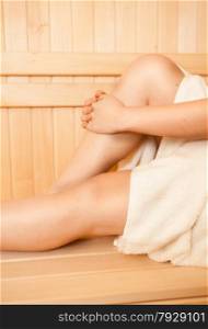 Closeup photo of woman touching feet on bench at sauna