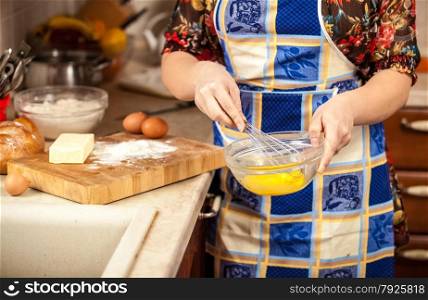 Closeup photo of woman whisking eggs in glass bowl