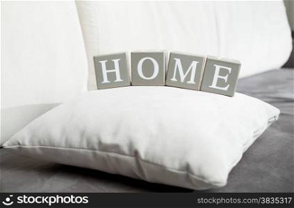 Closeup photo of word Home spelled on wooden blocks lying on sofa