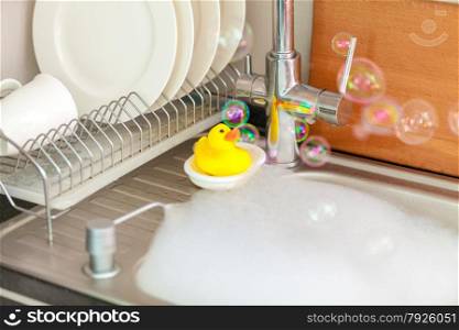 Closeup photo of yellow duck on kitchen sink in foam